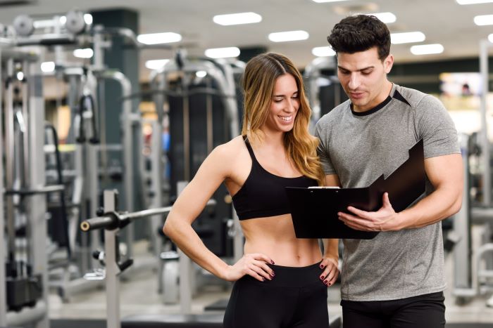 man and woman dresses in sports clothing food education standing in the middle of the gym