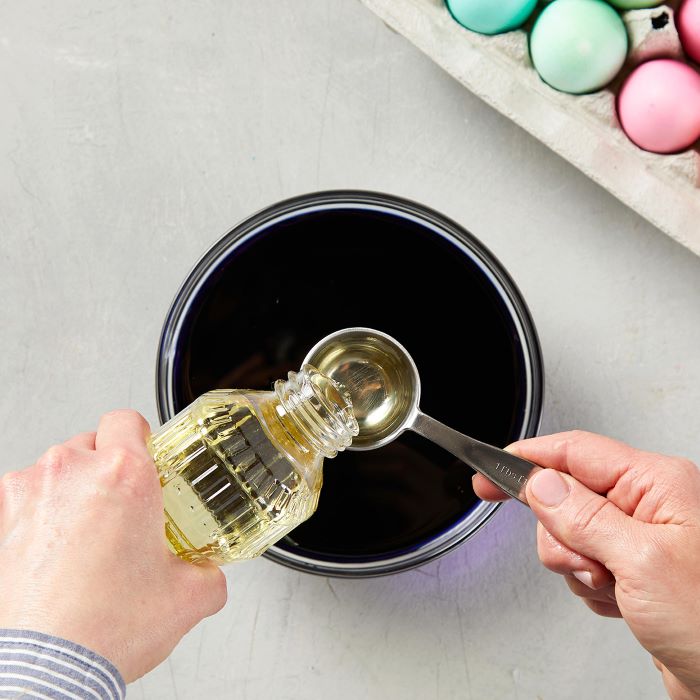 oil being poured into a measuring spoon step by step diy tutorial how to dye eggs with food coloring