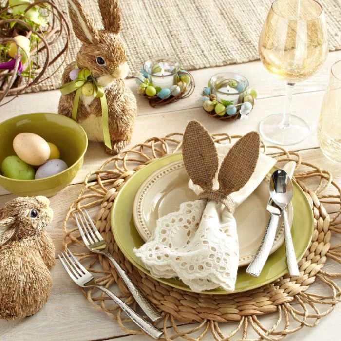 plate setting with white cotton napkin with bunny ears easter decorations small bunny figurines around it