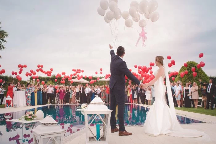 pool wedding home wedding ideas bride and groom standing next to the pool releasing white balloons