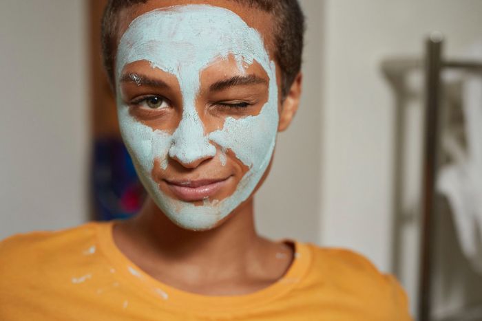 skin care masks woman wearing blue mask on her face wearing yellow t shirt with pixie cut