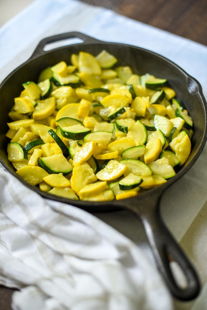 small black skillet filled with summer squash and zucchini pieced summer squash recipes placed on white cloth