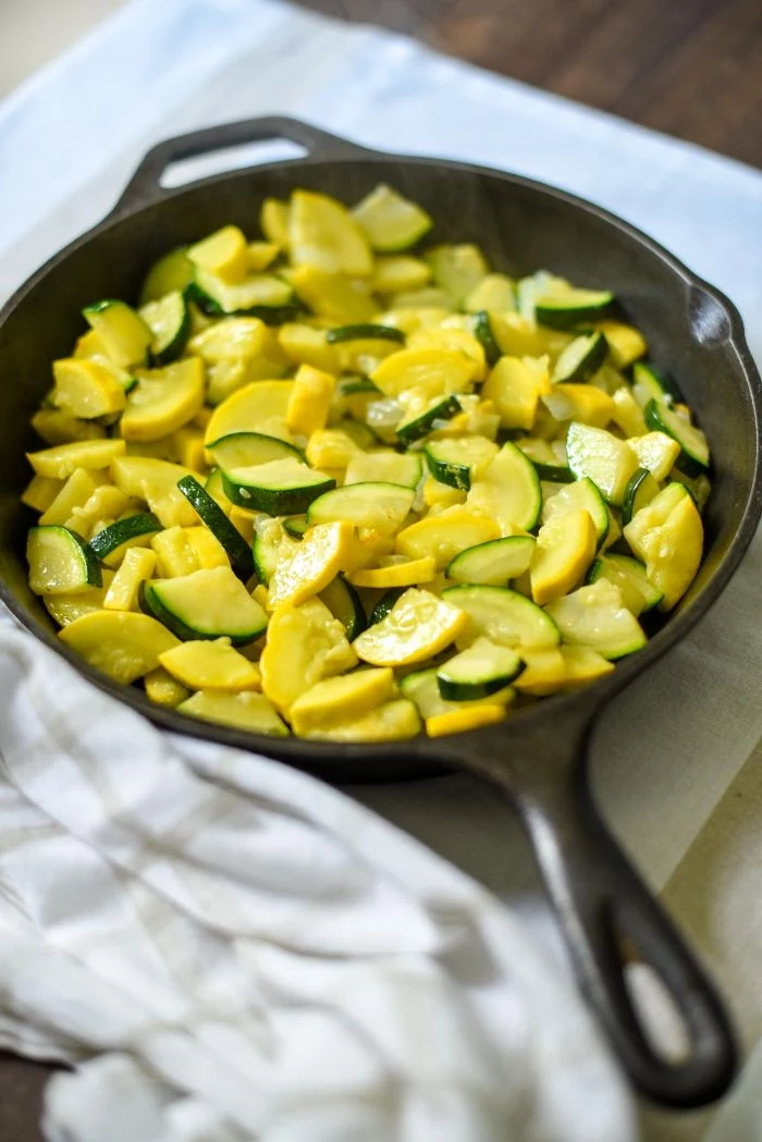 small black skillet filled with summer squash and zucchini pieced summer squash recipes placed on white cloth