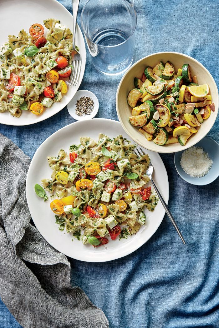 squash recipes bowtie pasta with yellow and red cherry tomatoes basil pesto placed on white plates