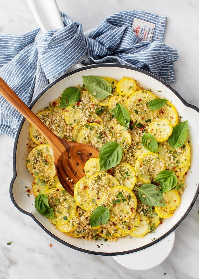 squash slices inside white saucepan zucchini and yellow squash recipes garnished with cheese and basil leaves