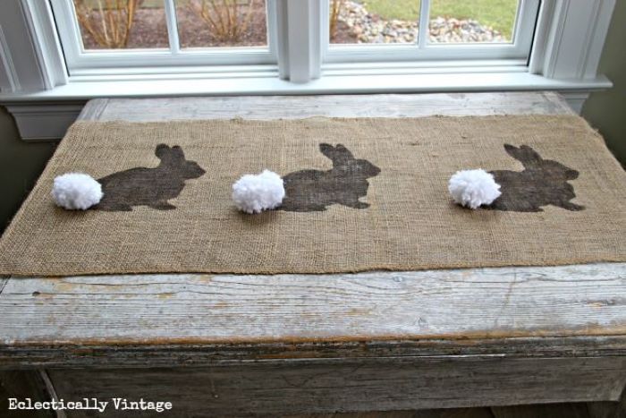 table runner placed on wooden table easter table décor bunny patterns with whtie pom poms for tails