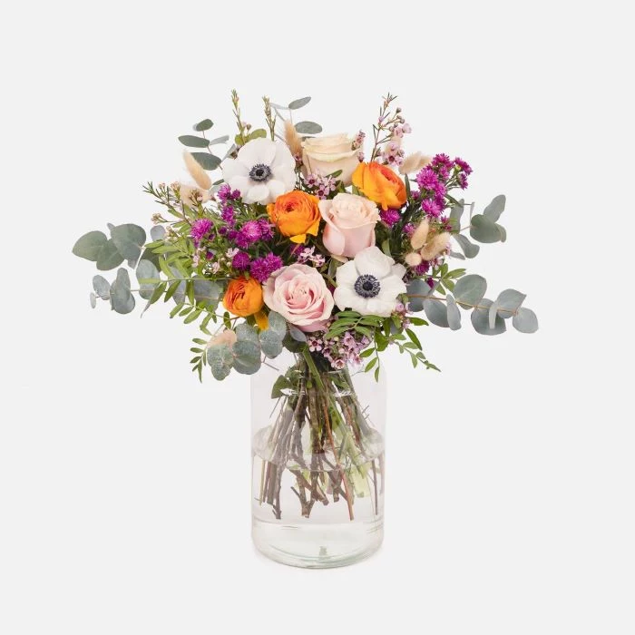 vase filled with water placed in front of white background flowers to give as gifts colorful flower bouquet inside
