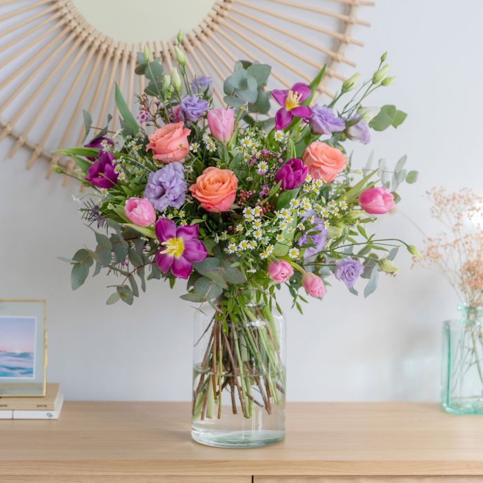 vase placed on wooden cabinet flowers to give as gifts flower bouquet in pink purple and green in it