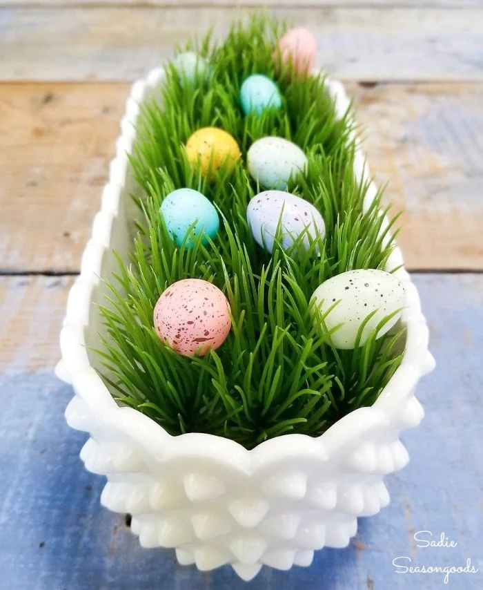 white ceramic pot filled with faux green grass diy easter decorations eggs inside in blue pink yellow purple