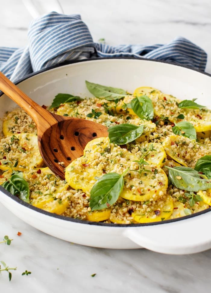 white saucepan filled with squash zucchini and yellow squash recipes garnished with cheese and basil leaves
