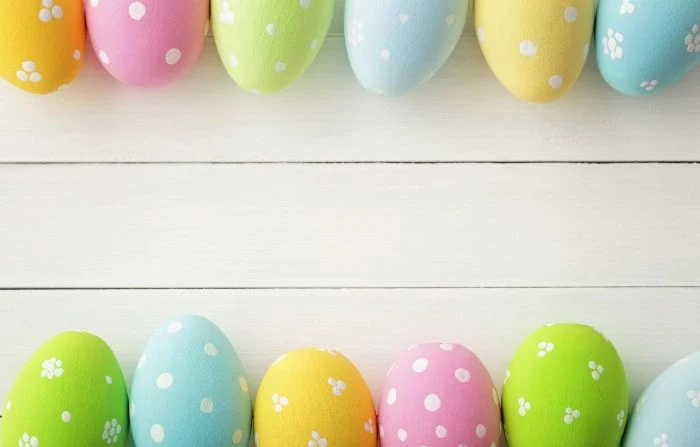 white wooden surface easter background eggs in different colors in the top and bottom edges of the photo