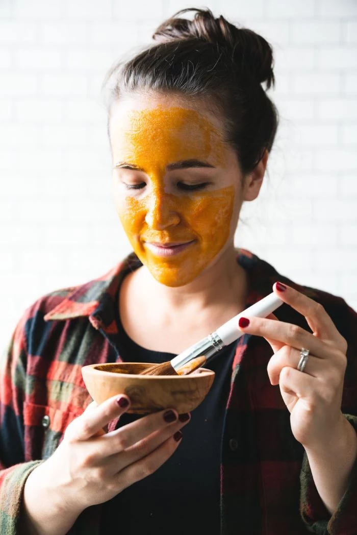 woman putting on yellow face mask how to make a face mask for skin wooden bowl and brush