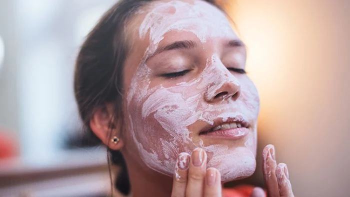 woman putting white mask on her face diy face masks with closed eyes