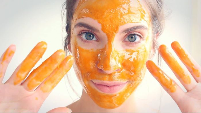 woman putting yellow face mask on her face skin care masks white background