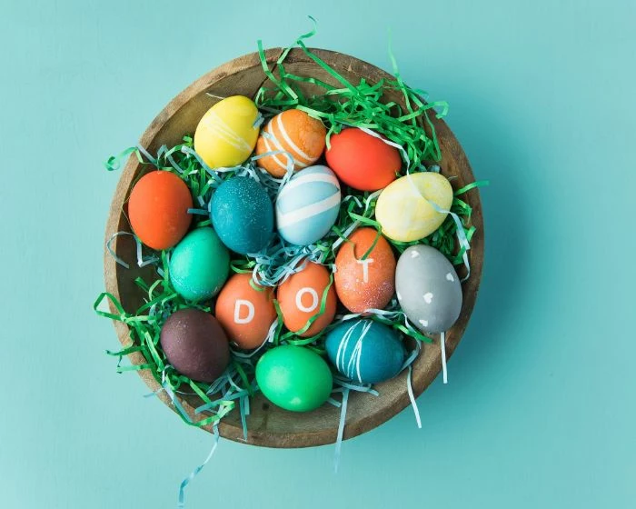 wooden bowl filled with eggs and green paper easter egg coloring decorated eggs