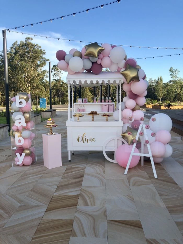 baby shower ideas for girls food cart with desserts decorated with pink purple gold balloons baby blocks on the side filled with balloons