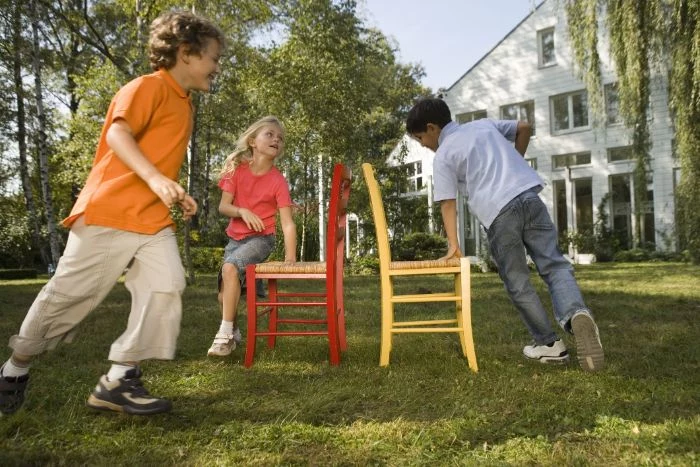 backyard games for kids three kids running around two chairs playing musical chairs