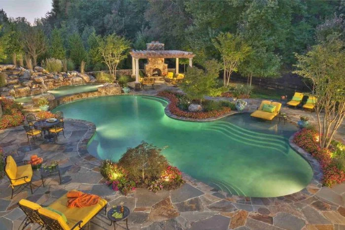 backyard pool ideas free flow pool with lights surrounded by rocks and garden furniture