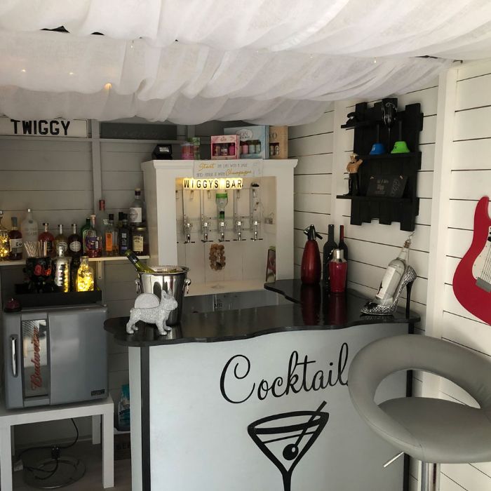 backyard tiki bar small bar with black countertops shelf with different bottles mini fridge gray leather stool