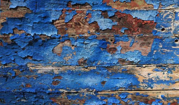 blue paint in pieces coming off of wooden surface lead poisoning close up photo
