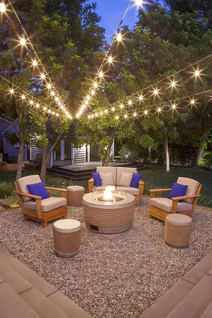 blue throw pillows on garden furniture backyard string lights hanging above from the trees