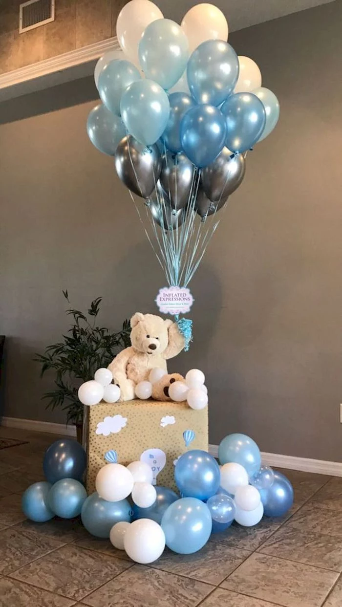 blue white gray balloons being held by teddy bear sitting on a large box baby shower decorations