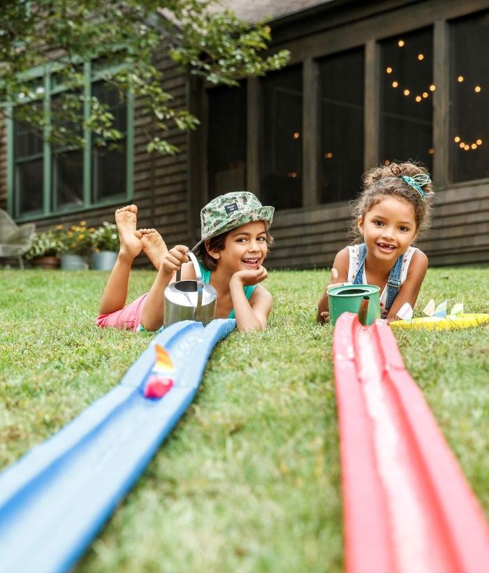 boy and girl playing outdoor games for kids pool noodles cut in half water poured on them for mini boat race