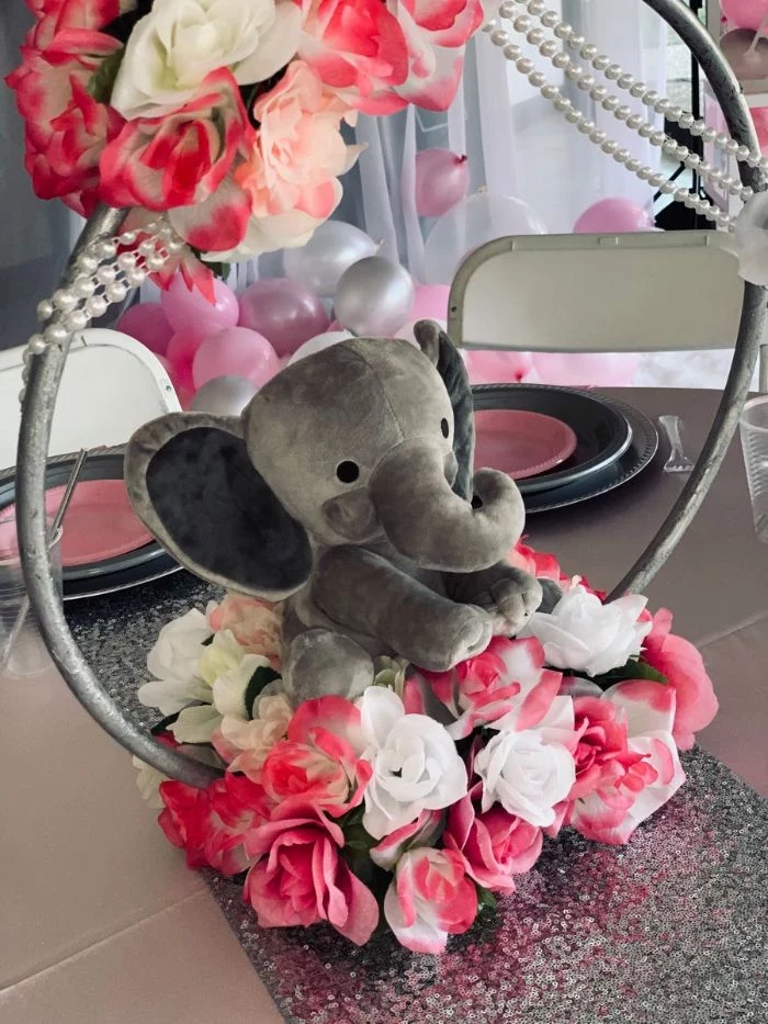 centerpiece made with faux roses velvet toy elephant baby shower decorations placed on silver glitter table runner