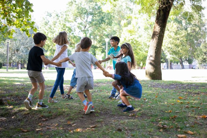 children holding arms in a circle fun things to do outside playing on a field covered with grass