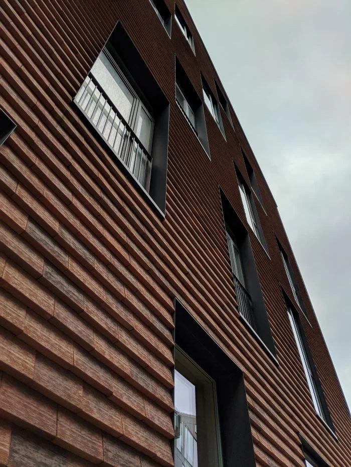 close up photo of tall apartment building with wood siding lots of windows home siding