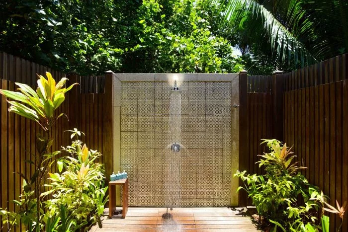 colorful tiles on the wall with the shower wood outdoor shower wood enclosure plants around it