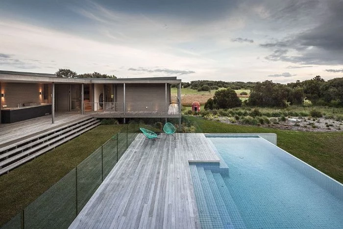 contemporary house with infinity pool garden furniture next to it pool landscaping ideas