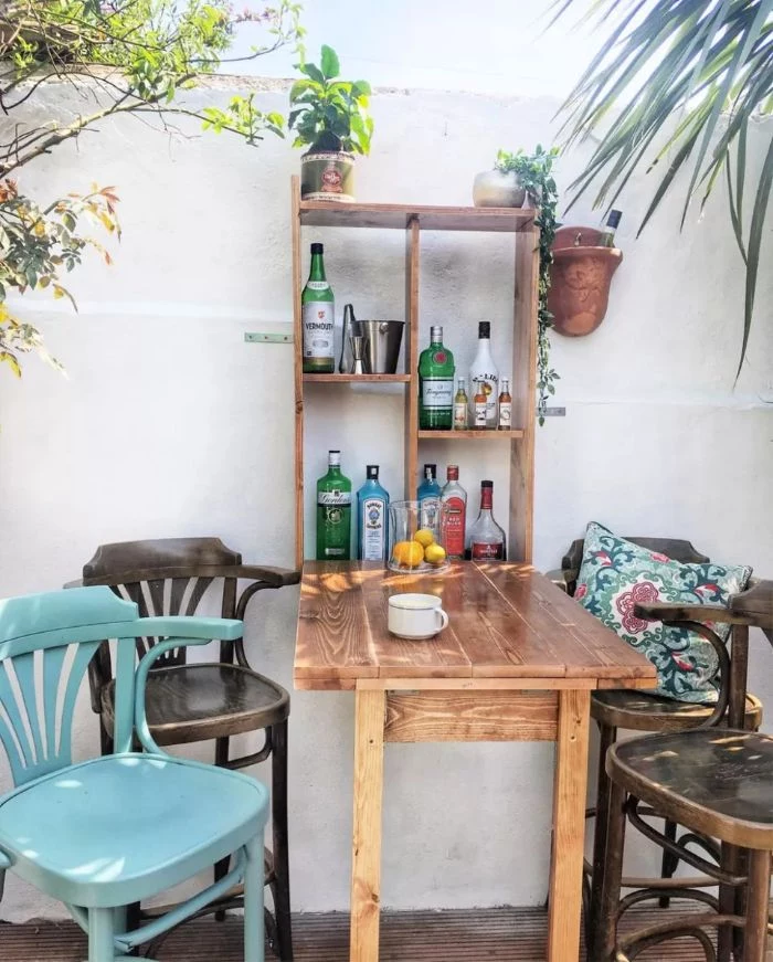 different chairs around small bar outdoor patio bar four shelves with bottles and potted plants