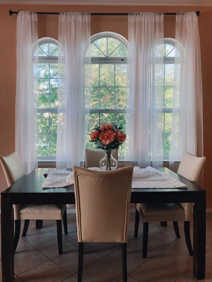 dining room with three tall windows window installation square black wooden table four white leather chairs