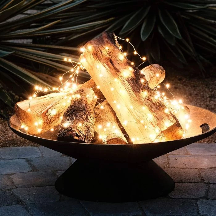 faux fire pit backyard lighting ideas logs arranged in metall pit wrapped with led fairy lights