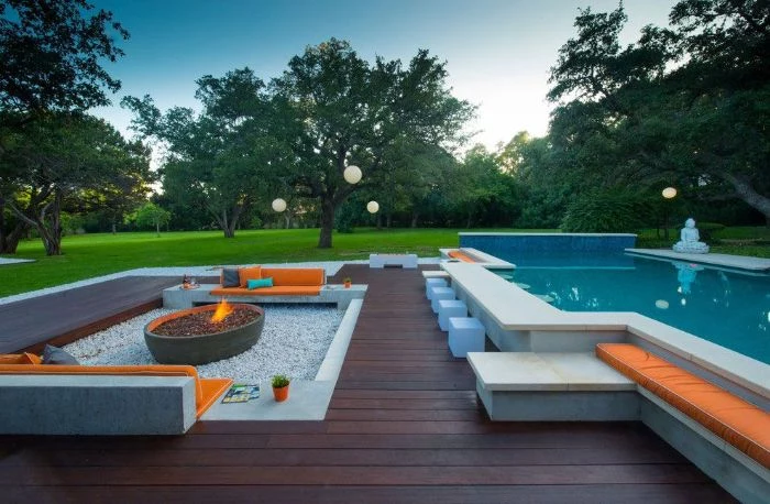 fire pit surrounded by stone benches with orange cushions backyard pool ideas wooden floor