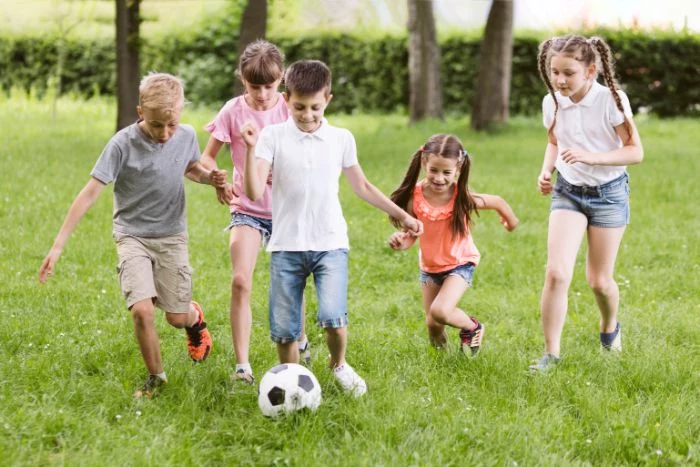five kids playing football on field covered with green grass things to do outside soccer