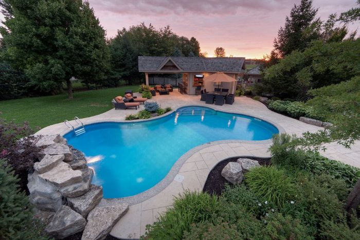 free flow pool in the back of small house pool landscaping ideas surrounded by rocks trees and bushes