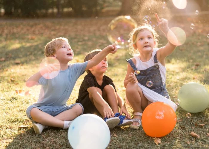 fun things to do outside three kids popping soap bubbles balloons around them