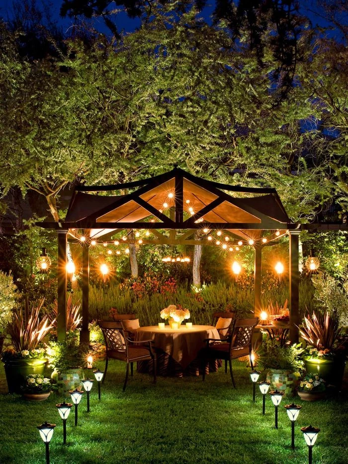garden furniture under tent with strings of lights on the ceiling outdoor hanging lights solar lamps along the pathway