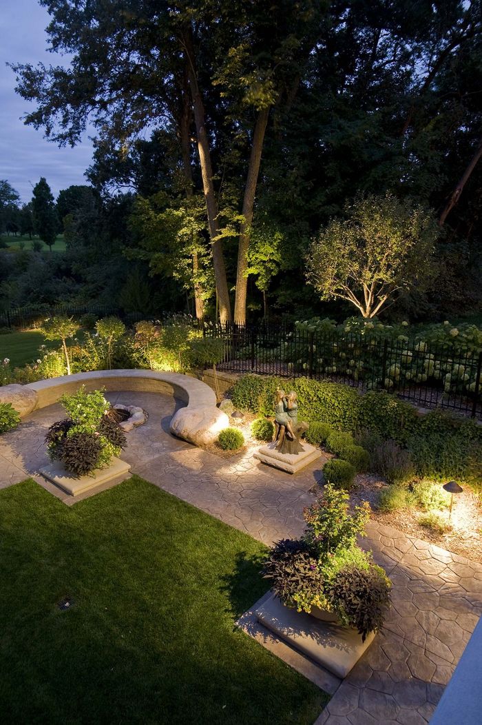 garden with lights under the plants and trees outdoor string lights stone pathway and bench