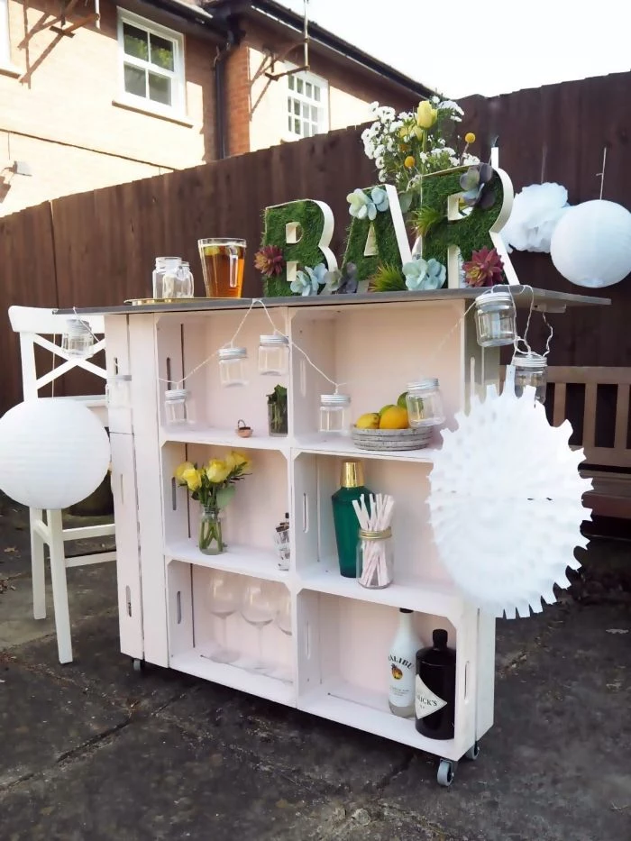 green bar sign on top of white wooden trolley made of crates home bar ideas on a budget different bottles and glasses on it