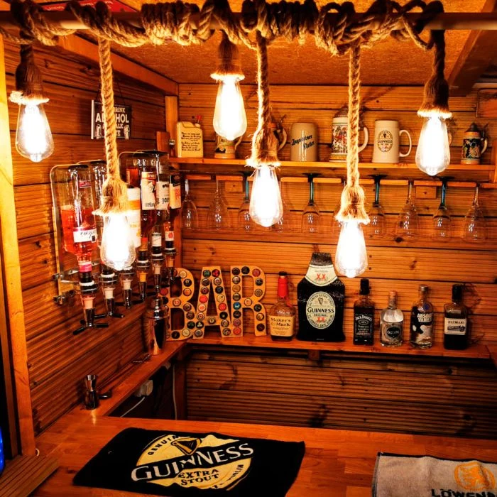 hanging lights with rope over wooden bar outdoor patio bar shelves with different alcohol and glasses
