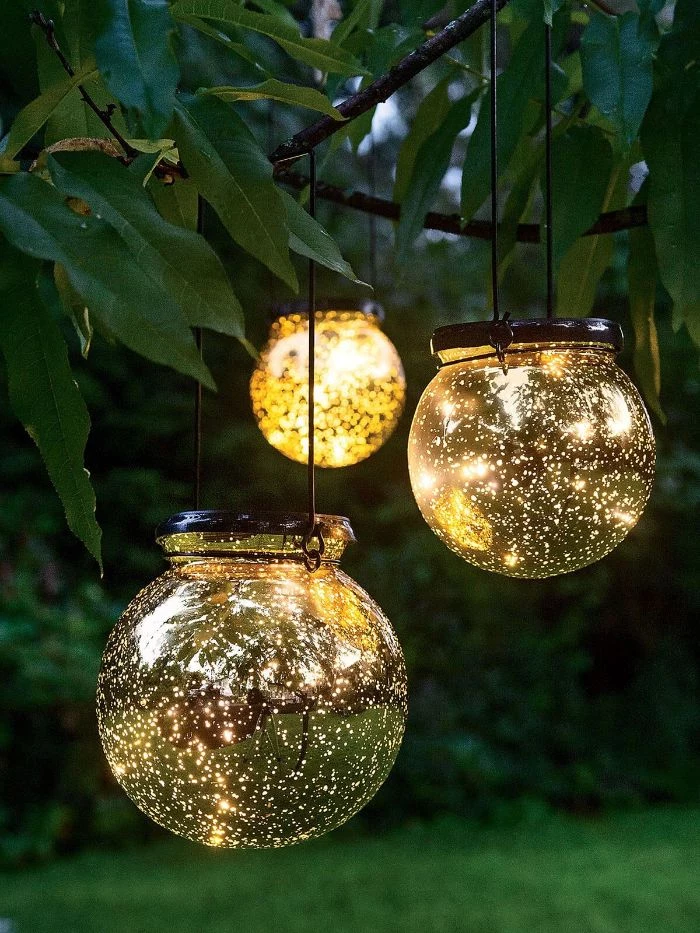 jars filled with small fairy lights outdoor string lights hanging from a tree with warm glow