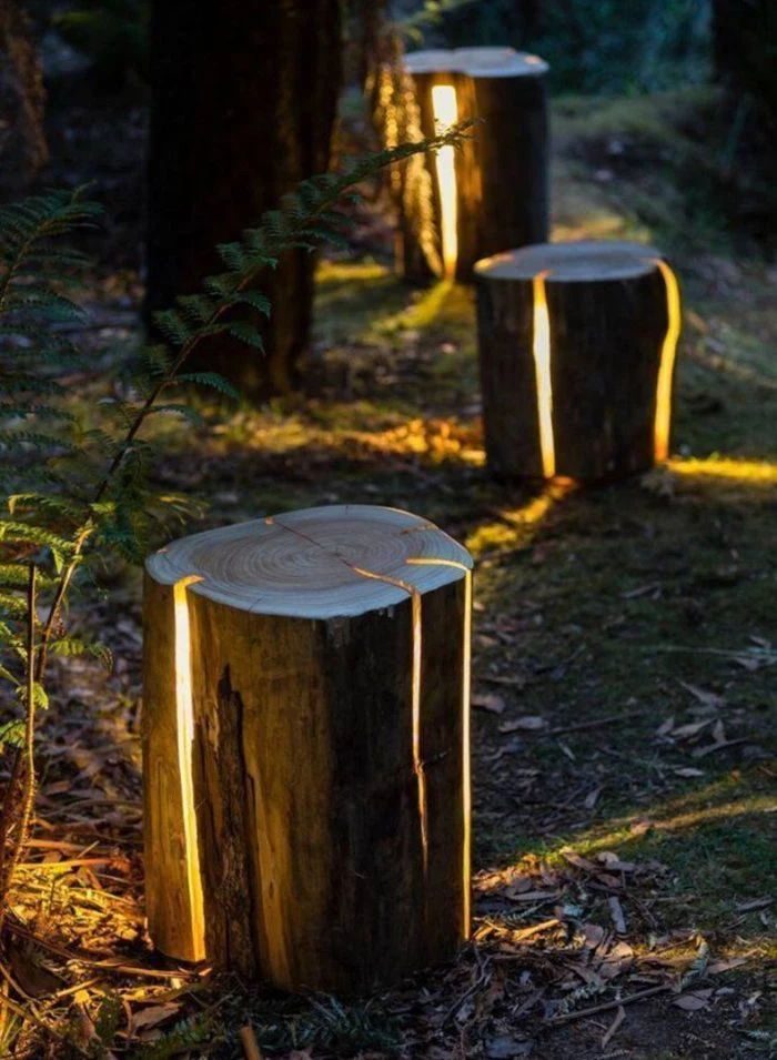 log lamps outdoor lighting ideas logs with led lights on the inside placed along a pathway next to trees