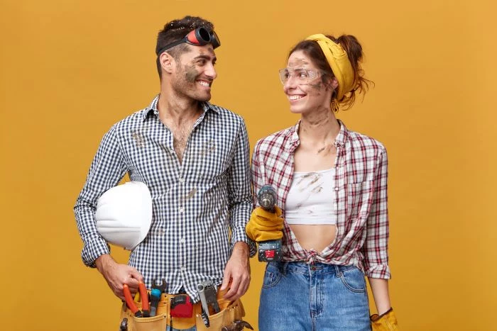 man woman wearing plaid shirts safety goggles different tools home remodeling yellow background