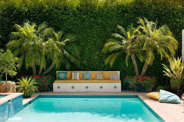 mediterranean style decor inground pool design bench with colorful throw pillows palm trees and flowers next to pool