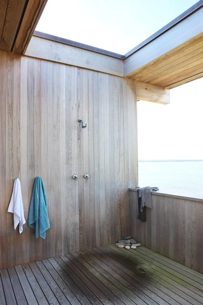 open ceiling and side outdoor shower enclosure made of wood with wood floor hooks for towels