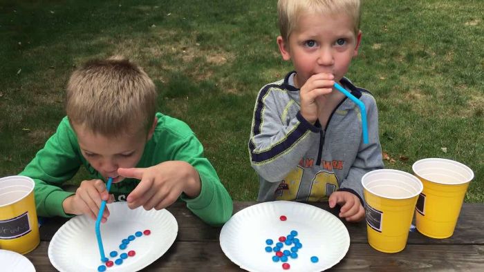 outdoor fun for kids two boys standing next to table trying to take candy from a plate with a straw