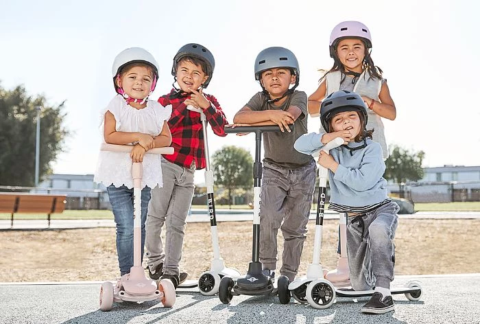 outdoor games for kids boys and girls wearing helmets riding scooters posing for a photo